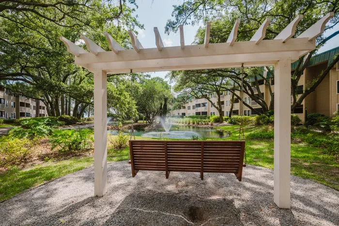 Relaxing pergola swing overlooking a scenic pond and fountain