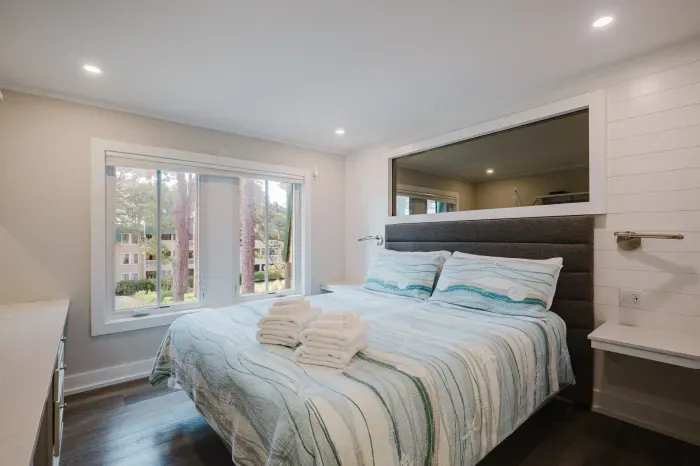 Bright, modern bedroom with large windows and peaceful treetop views