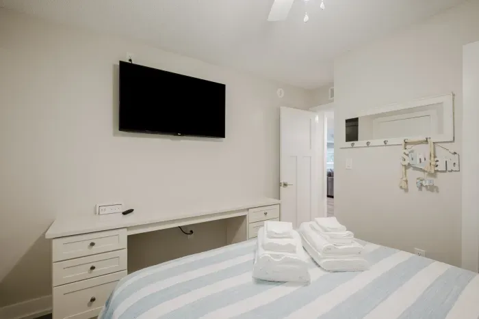 Bright bedroom with TV, workspace, and fresh linens