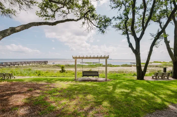 Waterfront lawn with shaded pergola swing and serene coastal views