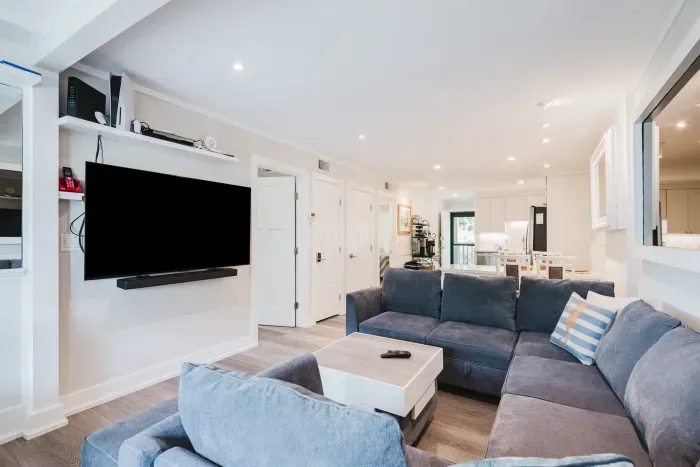 Bright open living room with large sectional, TV, and seamless kitchen flow