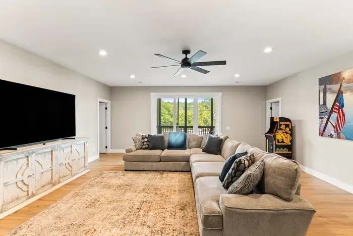 Big sectional, an arcade cabinet, and a wall-size TV. Slider opens to the lower deck for wet-swimsuit traffic.