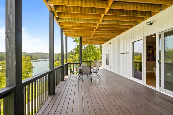Dining table under cover on the walkout level, with hooks for towels and life jackets by the door.