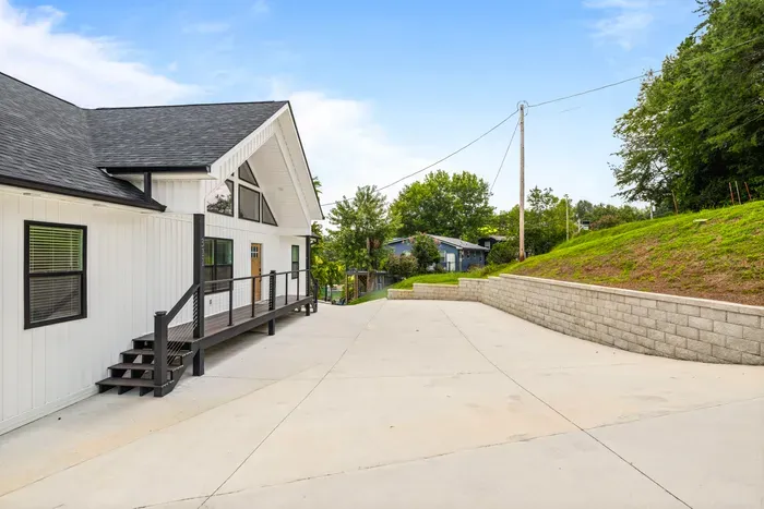 Wide concrete drive with room for several vehicles and a trailer, plus a retaining wall keeping the hillside back.