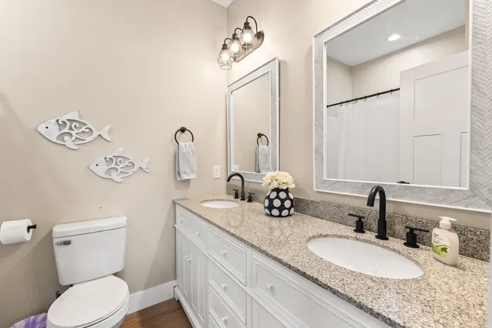 Bright double-vanity bathroom with granite countertops, modern finishes, and stylish coastal charm.