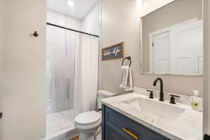 Tiled walk-in shower, navy vanity, and quartz counters. One of the nicer baths in the house.
