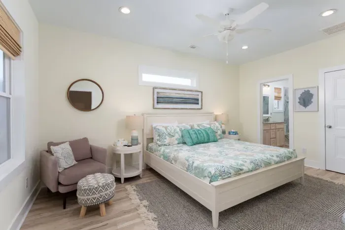Expansive primary bedroom with king sized bed, accent chair for seating, and TV.