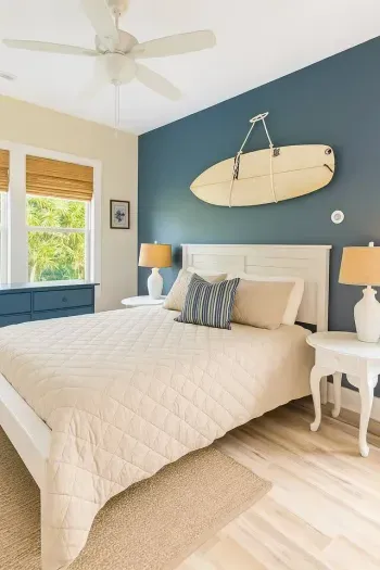Drift off to sleep with coastal vibes all around.  This serene bedroom features a surfboard accent above the bed for the perfect beach house touch.