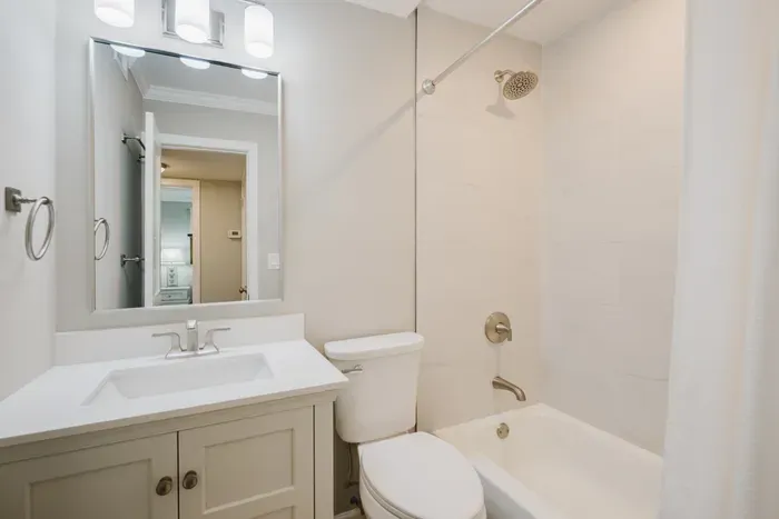 Renovated full bath with a tiled tub-shower combo, quartz vanity, and plush towels. Opens directly to the hall for easy shared access.