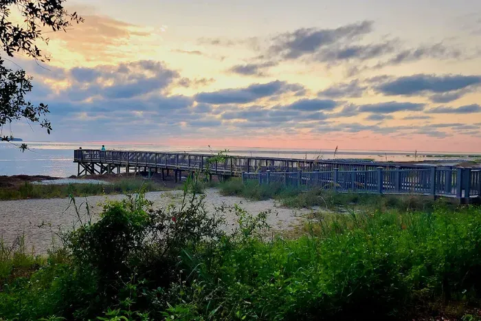 Tranquil beach with dock seating and stunning sunset views.