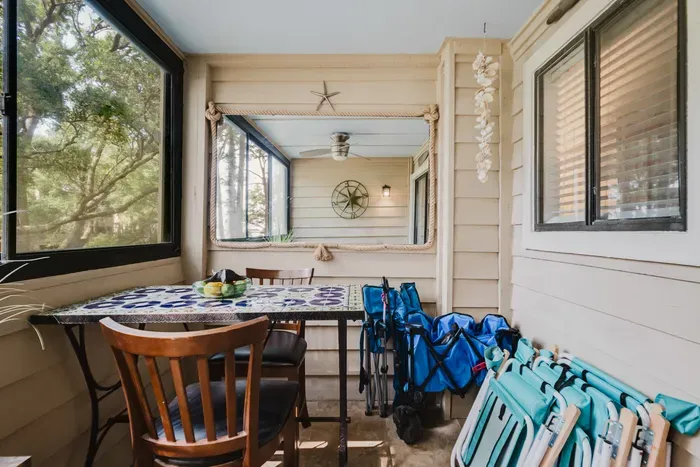 Cozy screened porch with dining nook, tree views, and beach gear ready