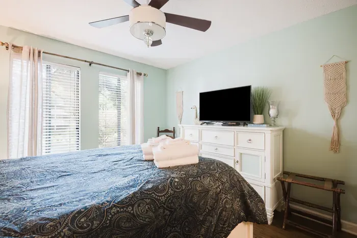 Bright, cozy bedroom with TV, natural light, and a relaxing vibe