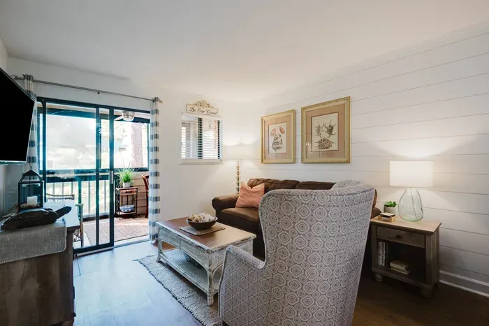 Bright coastal living room with cozy seating and screened balcony access