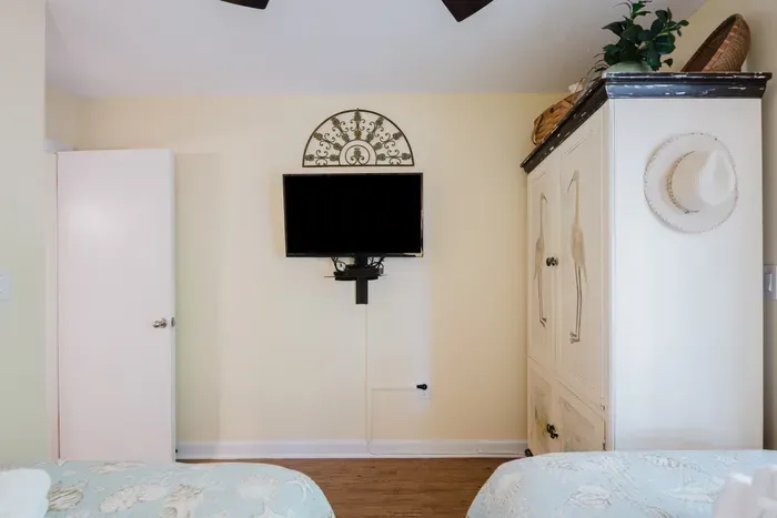 Cozy coastal bedroom with twin beds, TV, and spacious wardrobe