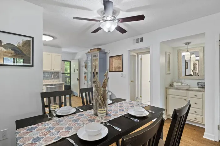 Dining table has colorful, patterned tablecloth with set of plates, silverware, and glasses.