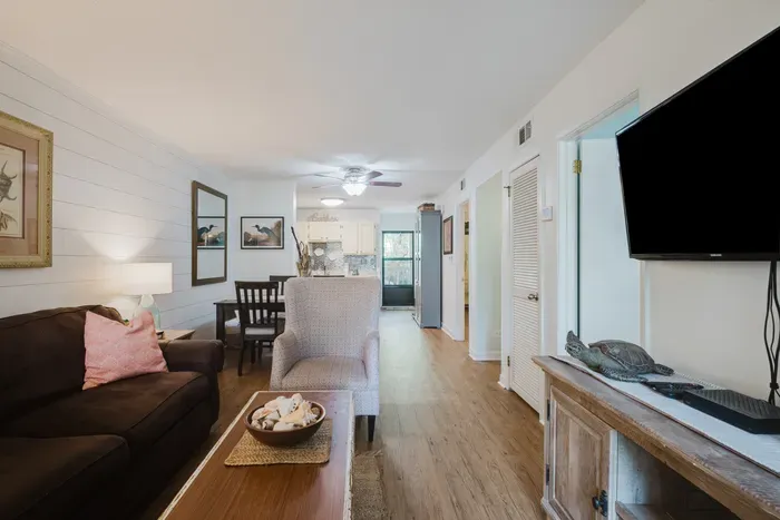 Bright open living space with TV, dining area, and airy coastal charm
