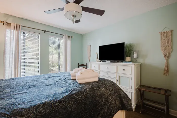 Bright, cozy bedroom with TV, natural light, and fresh guest-ready touches