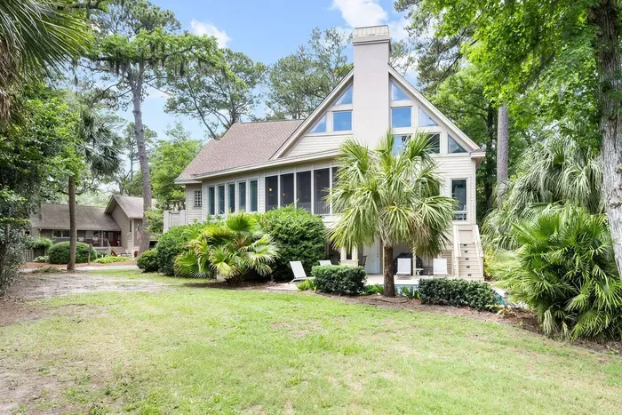 The back of the house from the lawn: soaring window wall, screened porch, and the pool tucked in beside it.