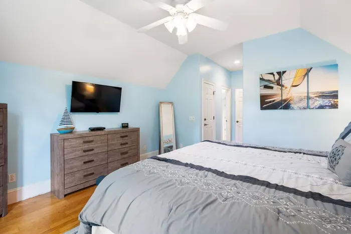 Upstairs king suite under a vaulted ceiling with a smart TV and its own bath.