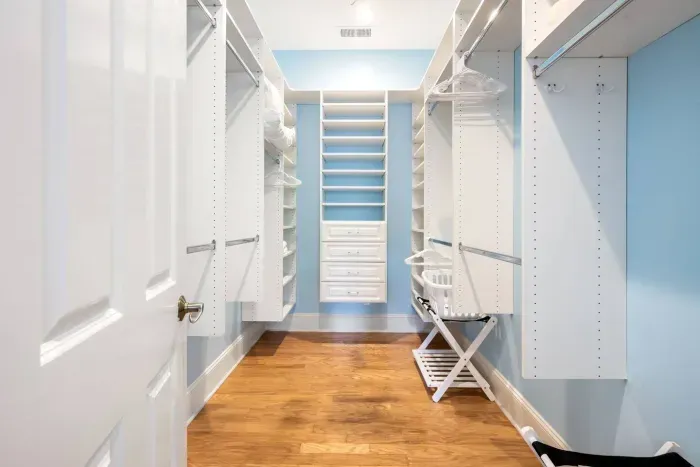 Walk-in closet with built-in shelving, drawers, hangers, and a luggage rack ready to go.