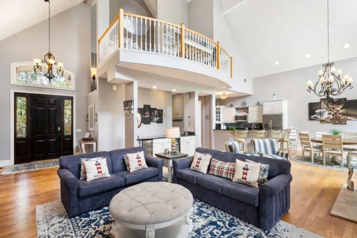 The whole main level opens up at once. Living, dining, kitchen, and the curved loft balcony overhead.