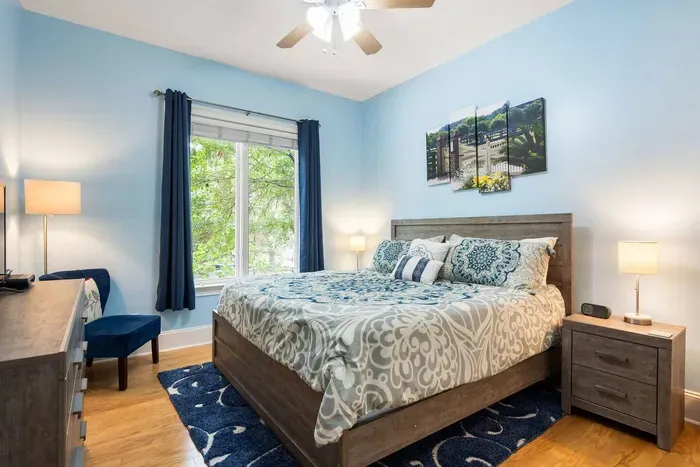 Guest bedroom with a king bed, smart TV, and a tree-lined view. Blackout curtains for sleeping in.
