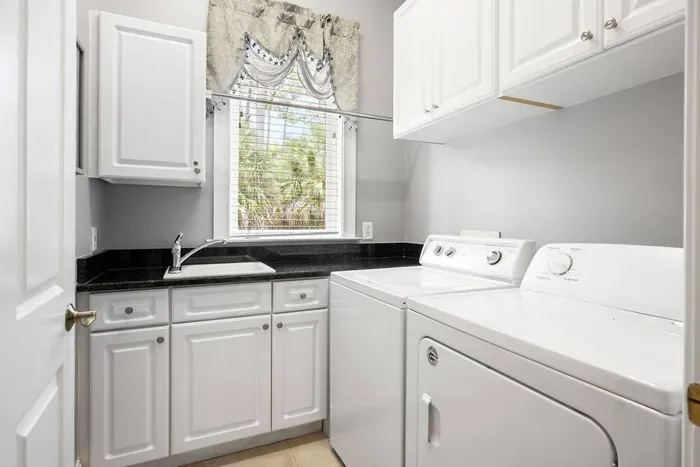 Full-size washer and dryer with a utility sink and counter space for folding.