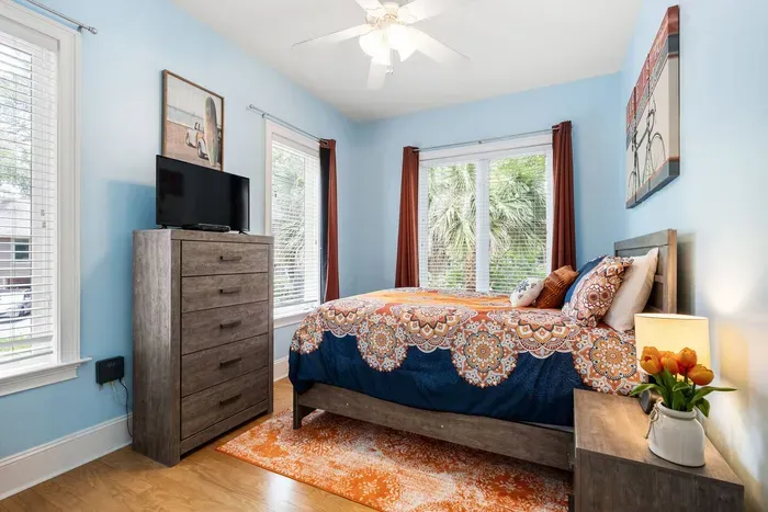 Fourth bedroom with a queen bed, smart TV, and windows on two walls.