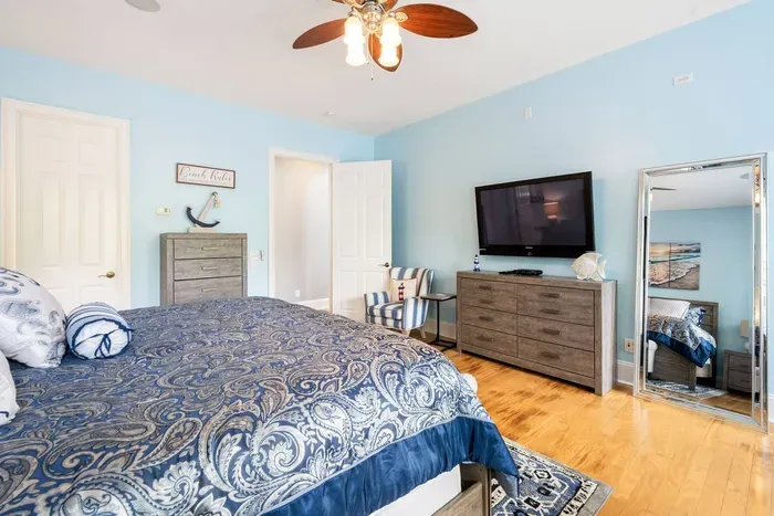 Room to spread out in the primary: full dresser, smart TV, and a floor-length mirror.