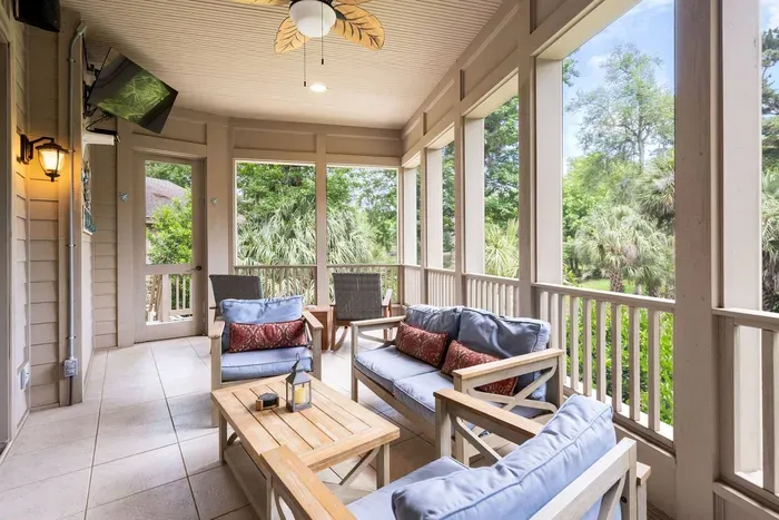 The screened porch: deep cushioned seating, an outdoor TV, and a ceiling fan for the warm afternoons.