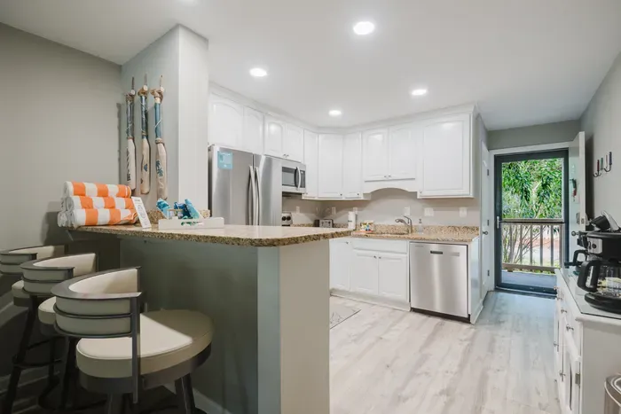 Breakfast bar seats three, beach towels stacked and ready, and a back door out to your private entry landing.