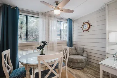Bright coastal dining nook with sunny windows and charming nautical style