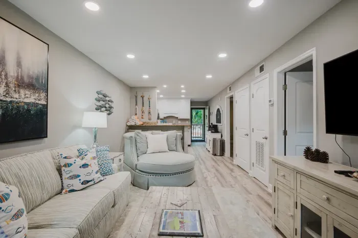 Bright coastal living space.  The full length of the villa in one view: living room, kitchen, coffee bar, and the door to your entry landing.