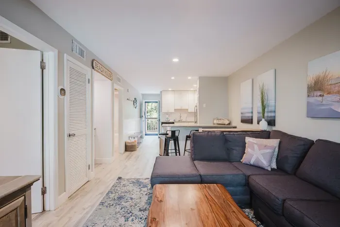 Bright coastal living room with sectional sofa and open kitchen seating