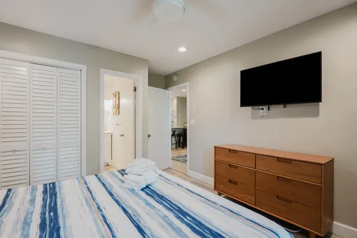Cozy bedroom with smart TV, dresser, closet, and easy bathroom access
