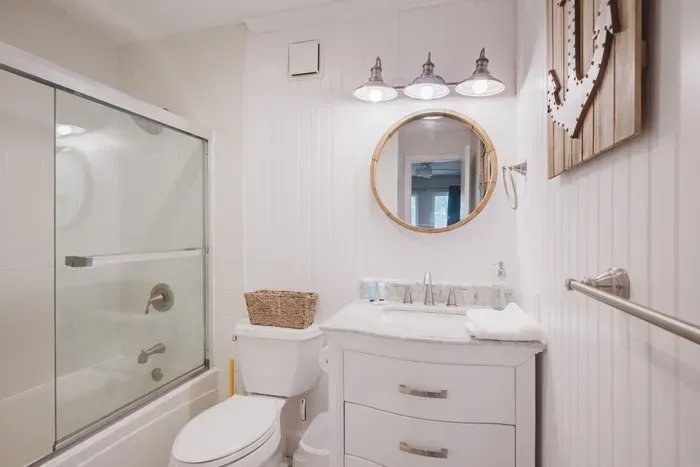 Bright modern farmhouse bathroom with glass shower and marble vanity