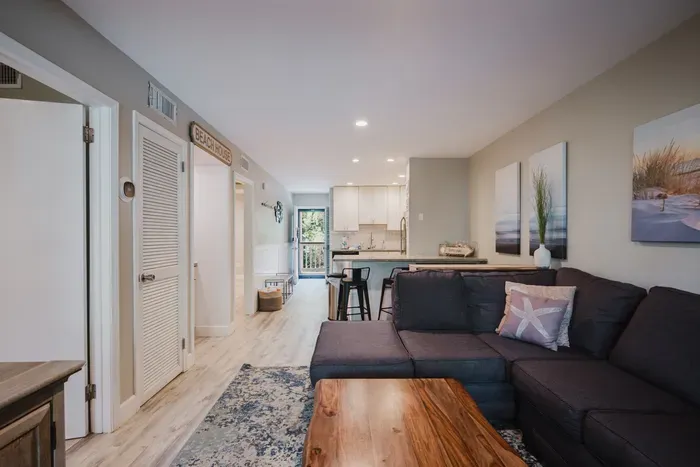 Cozy coastal living room with sectional, bar seating, and bright modern kitchen