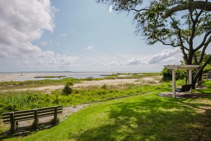 Peaceful beachfront lawn with swing, bench, and sweeping water views