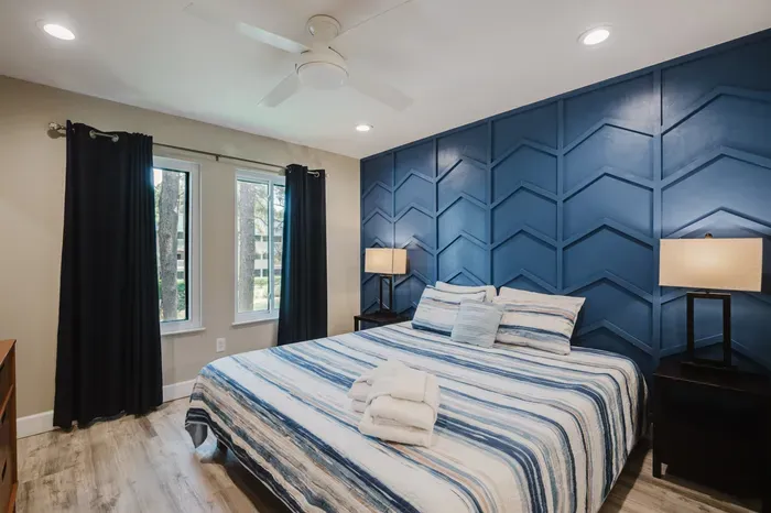 Stylish king bedroom with bold accent wall, natural light, and blackout curtains