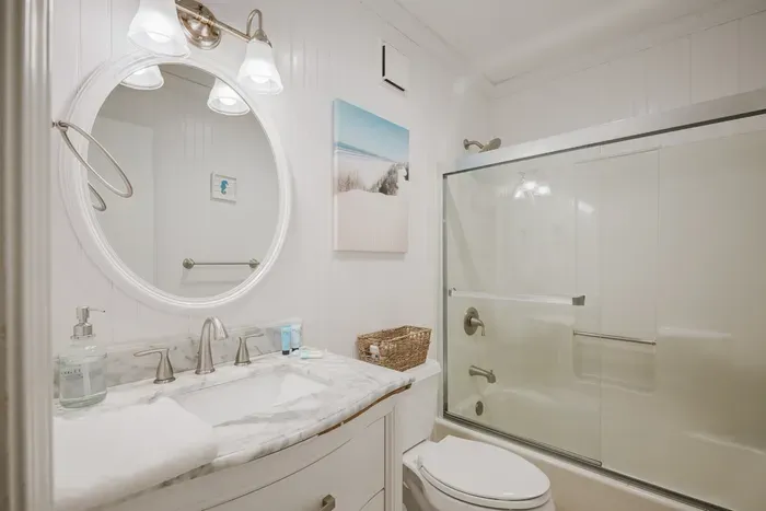 Bright coastal bathroom with marble vanity and glass shower-tub combo