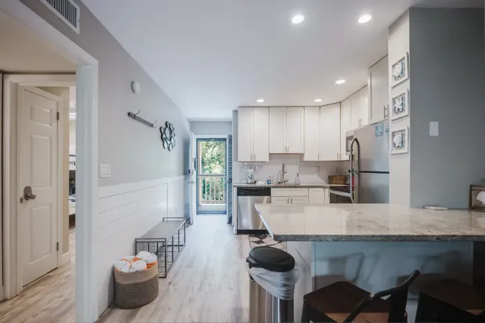 Bright modern kitchen with granite bar, stainless appliances, and coastal style