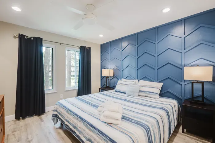 Stylish king bedroom with bold blue accent wall and natural light