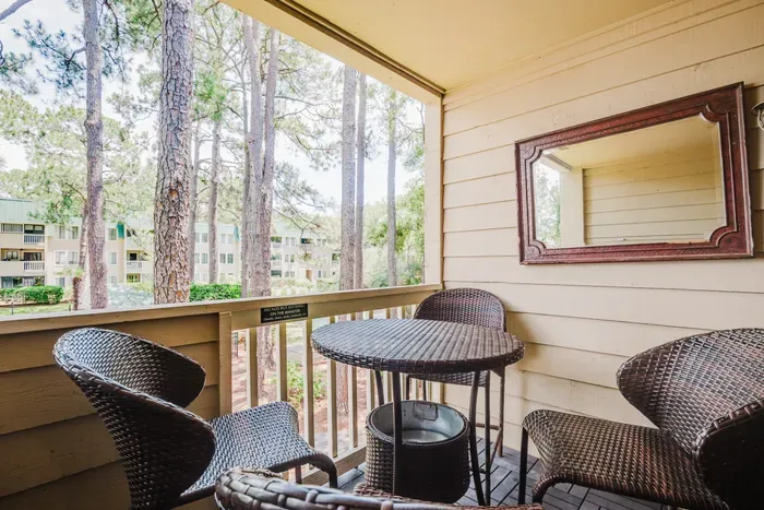 Cozy private balcony with wicker seating and serene wooded views