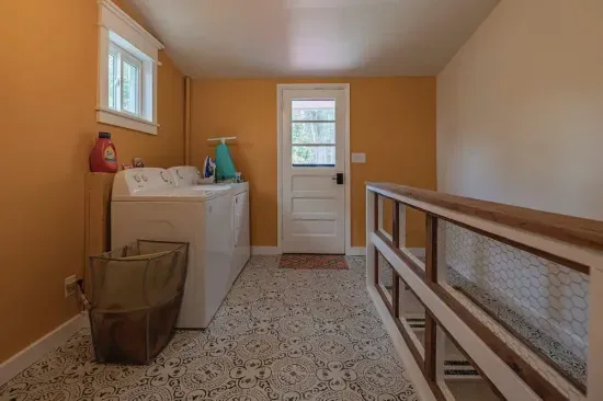 The laundry room includes a washer, dryer, ironing board, and iron, with detergents available for guest use. A door leads directly to the back porch for easy outdoor access.