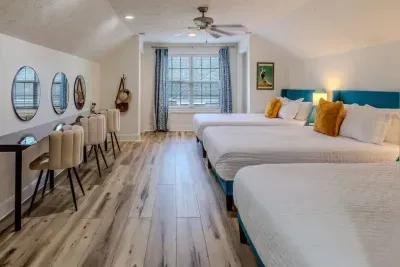 This spacious suite features three queen beds with crisp white linens and accent pillows, ideal for group stays. 

An 11-foot live-edge vanity with three stations and dual hair dryers makes it perfect for ladies getting ready together.
