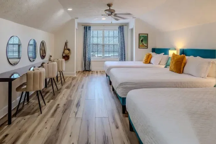 This spacious suite features three queen beds with crisp white linens and accent pillows, ideal for group stays. 

An 11-foot live-edge vanity with three stations and dual hair dryers makes it perfect for ladies getting ready together.