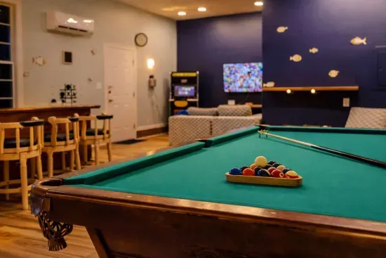 A one-of-a-kind man cave features a 9-ft slate billiards table, custom live-edge slab bar, and retro arcade cabinet with classic games. Bold lighting, wood accents, and a laid-back vibe make it the perfect space for fun, relaxation, and entertaining.