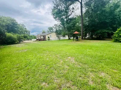 Side yard is great for kids to play ball. The property is surrounded by trees on 3 sides. On the left side and back of house there is a fenced in yard area.