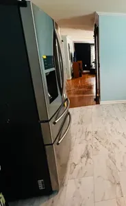 View from kitchen through house to living room. Extra large refrigerator on the left side of wall.