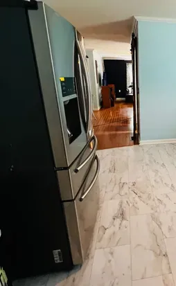 View from kitchen through house to living room. Extra large refrigerator on the left side of wall. 